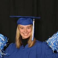 student in cap and gown with pom poms